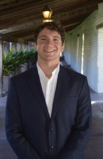 boy in suit with house behind him